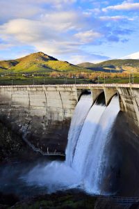 Countryside hydrodam with three outlets open releasing water into river below