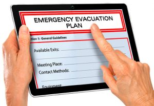 Close up of hands touching tablet with emergency evacuation plan document